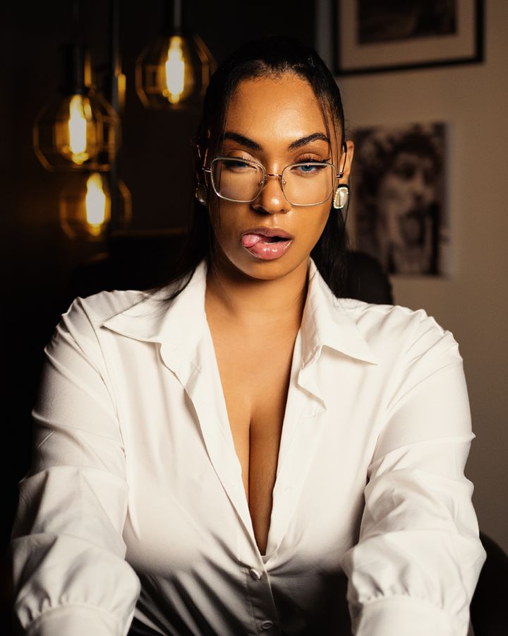 Hazel in a white shirt and glasses, looking into the camera